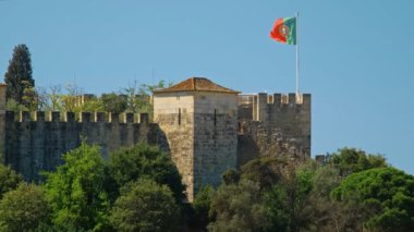 Portekiz Lisboa 'daki Saint George Kalesi Castelo de Sao Jorge. Yürüyen turistler ve büyük Portekiz bayrağı.