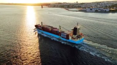 Tagus Nehri 'nin hava aracı görüntüsü ve kargo konteynır gemisi gün batımında Lizbon limanından ayrılıyor. Lizbon, Portekiz. Yörünge paraşütü atışı