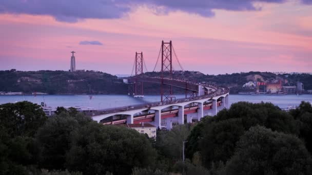 ミラドゥロ ベリオ アルヴィートからのリスボンの景色タガス川の観光の視点 4月25日の橋の交通 そして夜の夕暮れのキリスト キング像 ポルトガルのリスボン — ストック動画