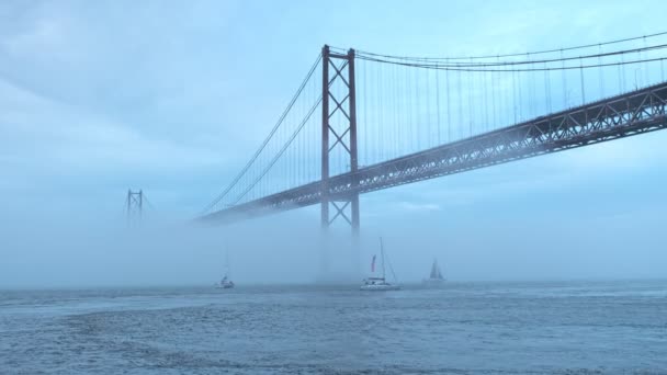 里斯本著名的旅游地标里斯本的阿布里尔桥25号的景观 它在浓雾中连接着里斯本和阿尔马达 游艇从船底经过 葡萄牙里斯本 — 图库视频影像