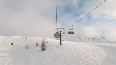 Kablolu sandalyede kayak kaldırmanın FPV bakış açısı Dolomitlerde alp kayağı için yükseliyor. İtalya 'da Dolomitler' de kayak yapan insanlarla kayak merkezi. Kayak alanı Belvedere. Canazei, İtalya