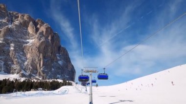 Kablolu sandalyede kayak kaldırmanın FPV bakış açısı Dolomitlerde alp kayağı için yükseliyor. İtalya 'da Dolomitler' de kayak yapan insanlarla kayak merkezi. Kayak alanı Belvedere. Canazei, İtalya