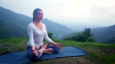 Yoga yapan kadın - Padmasana Lotus 'ta meditasyon yaparken gün batımında dağlarda poz veriyor.