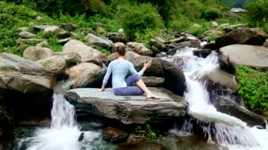 Yoga - Ardha matsyendrasana asana yaparken kadın - yarım spinal büküm poz Himalayalar Hindistan'da tropik şelale, açık havada egzersiz. Retro vintage etkisi filtre uygulanmış hippi tarzı görüntü.