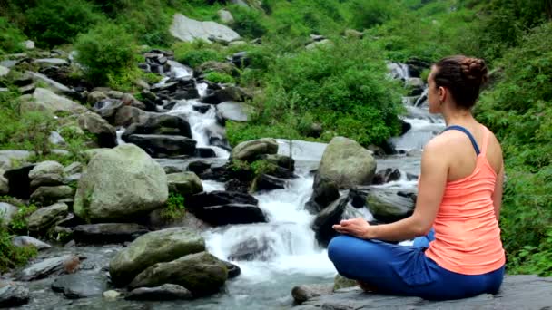 若いスポーティなフィット女性ヨガ 熱帯の滝で屋外 Padmasana 蓮のポーズで瞑想します ヒマーチャル プラデーシュ州 インド — ストック動画