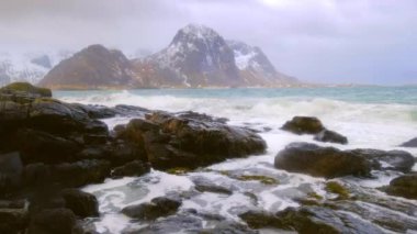 Gün batımında fiyorttaki kayalık sahilde Norveç dalgaları. Vareid Plajı, Lofoten Adaları, Norveç