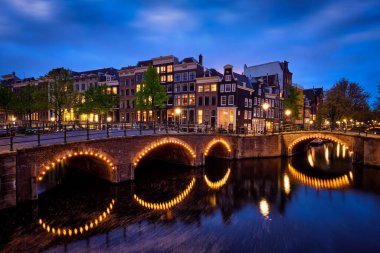 Amsterdam cityscape kanal, köprü ve ışıklı akşam alacakaranlık Ortaçağ evleri ile gece manzarası. Amsterdam, Hollanda
