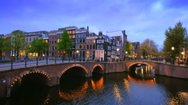 Amsterdam cityscape kanal, köprü ve ışıklı akşam alacakaranlık Ortaçağ evleri ile gece manzarası. Amsterdam, Hollanda