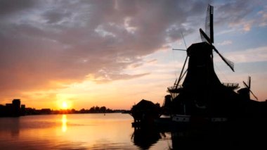 Hollanda 'nın ünlü turizm bölgesi Zaanse Schans' taki yel değirmenleri dramatik bir gökyüzü ile gün batımında. Zaandam, Hollanda