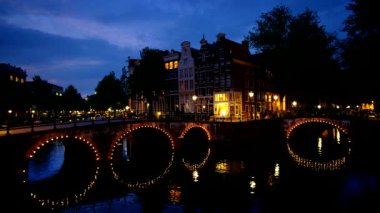 Amsterdam cityscape kanal, köprü ve ışıklı akşam alacakaranlık Ortaçağ evleri ile gece manzarası. Amsterdam, Hollanda