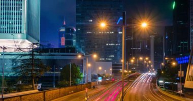 Hong Kong 'da gece vakti sokak trafiği. Ofis gökdelen binaları ve karayolu trafiği bulanık arabalarla aydınlık patikalar. Hong Kong, Çin