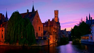 Bruges turistik merkezinin ünlü manzarası - Belfry ile Rozenhoedkaai kanalı ve geceleri ağaçlı kanal boyunca eski evler. Brugge, Belçika