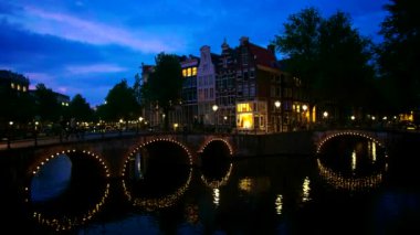 Amsterdam cityscape kanal, köprü ve ışıklı akşam alacakaranlık Ortaçağ evleri ile gece manzarası. Amsterdam, Hollanda