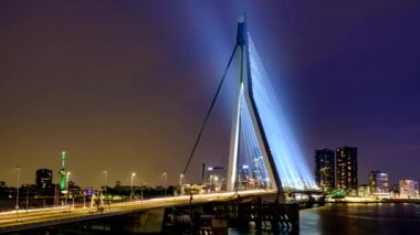 Gece, Nieuwe Maas üzerindeki Erasmus Köprüsü üzerindeki Rotterdam 'da sokak trafiğinin zamanlaması aydınlandı. Rotterdam, Hollanda. Kamera pan efekti