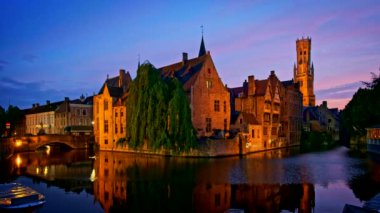 Bruges turistik merkezinin ünlü manzarası - Belfry ile Rozenhoedkaai kanalı ve geceleri ağaçlı kanal boyunca eski evler. Brugge, Belçika