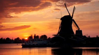 Hollanda 'nın ünlü turizm bölgesi Zaanse Schans' taki yel değirmenleri dramatik bir gökyüzü ile gün batımında. Zaandam, Hollanda