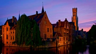 Bruges turistik merkezinin ünlü manzarası - Belfry ile Rozenhoedkaai kanalı ve geceleri ağaçlı kanal boyunca eski evler. Brugge, Belçika