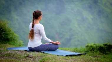 Yoga yapan bir kadın - Padmasana 'da meditasyon yaparken (Lotus Poz) gün batımında dağlarda