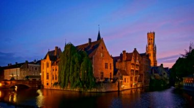Bruges turistik merkezinin ünlü manzarası - Belfry ile Rozenhoedkaai kanalı ve geceleri ağaçlı kanal boyunca eski evler. Brugge, Belçika