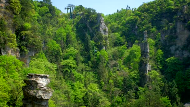 中国の有名な観光名所 張家江石柱は 中国湖南省のWulingyuanでケーブル鉄道の車のリフトと崖の山を カメラパン付き — ストック動画