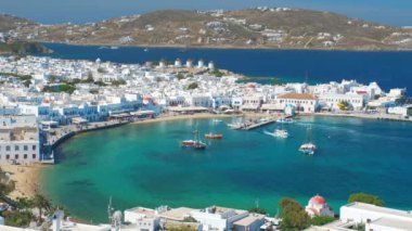 Meşhur yel değirmenleriyle Mykonos kasabası manzarası ve yaz günü tekneleri ve yolcu gemisi olan liman manzarası. Mykonos, Cyclades adaları, Yunanistan. Kamera kaydıyla