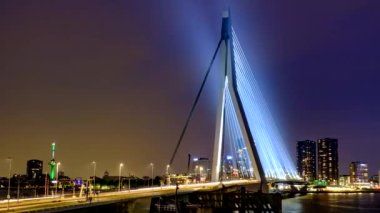 Gece, Nieuwe Maas üzerindeki Erasmus Köprüsü üzerindeki Rotterdam 'da sokak trafiğinin zamanlaması aydınlandı. Rotterdam, Hollanda. Kamera uzaklaşma efekti