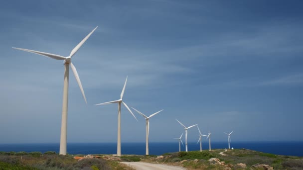 绿色可再生能源概念 风力发电机涡轮机发电 希腊克里特岛的风电场 有一个小的白色教堂 — 图库视频影像