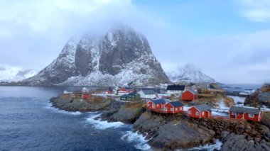 Norveç, Lofoten Adaları 'ndaki meşhur geleneksel balıkçı köyü Hamnoy' da kırmızı rorbu evleri var. Kışın kar yağarken