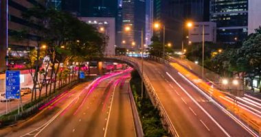 Hong Kong 'da gece vakti sokak trafiği. Ofis gökdelen binaları ve karayolu trafiği bulanık arabalarla aydınlık patikalar. Hong Kong, Çin. Kamera tavası