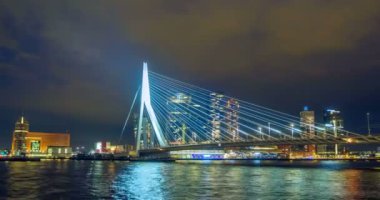 Gece vakti Rotterdam şehir manzarası ve Nieuwe Maas üzerindeki Erasmus köprüsü aydınlandı. Rotterdam, Hollanda. Kamera kaydıyla