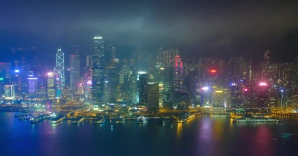 照らされた香港のスカイラインの街並みの空中風景は 夕方にビクトリア ハーバー上空の高層ビルを超えています カメラパンキング — ストック動画