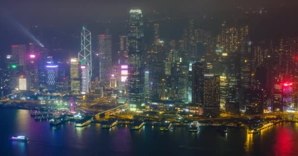 照らされた香港のスカイラインの街並みの空中風景は 夕方にビクトリア ハーバー上空の高層ビルを超えています カメラパンニング効果 — ストック動画