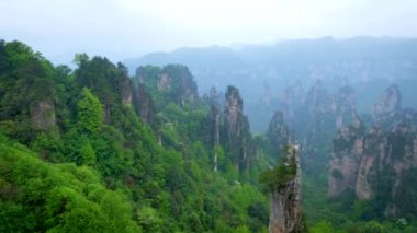 Çin 'in ünlü turistik merkezi - Zhangjiajie taş sütunları Wulingyuan, Hunan, Çin' deki sis bulutlarında uçurum tepeleri. Yatay kamera tavasıyla