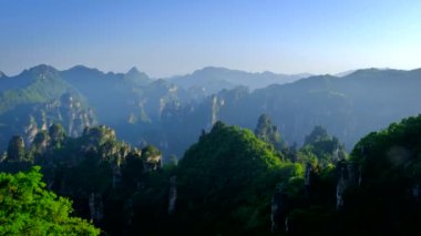 Çin 'in ünlü turistik merkezi Zhangjiajie taştan sütunları günbatımında Wulingyuan, Hunan, Çin' de uçurum tepelerinde. Kamera tavasıyla