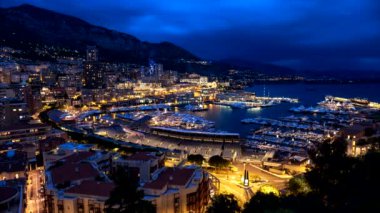 Monaco Monte Carlo marinası ve şehir silüeti zamanı. Hızlı hareket eden bulutlarla Monaco Limanı gece görüşü
