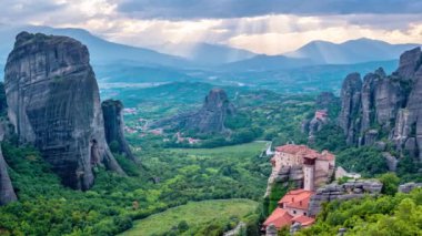 Yunanistan 'ın ünlü turizm beldesi Meteora' da, Rousanou manastırı ve St. Nicholas Anapavsa Manastırı 'nın üzerindeki güneş ışınlarıyla gün batımı zamanı. Kamera yansı hareketi