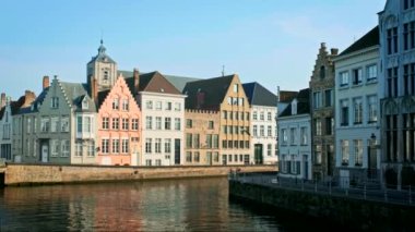 Belçika 'nın ünlü turist kasabası Bruges' de (Brugge) gün batımında eski evler ve kanallar. Sokaktan geçen bir araba. Yatay kamera tavasıyla
