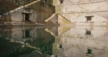 Toorji Ka Jhalra Baoli Stepwell 'deki su deposu. Jodhpur, Rajasthan, Hindistan' daki su kaynaklarından biri. Güneşli bir gün, su tabancaları havuzun duvarlarını yansıtıyor..