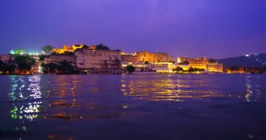 Pichola Gölü kıyısındaki ünlü lüks Udaipur Sarayı, gün batımında su dalgalarıyla aydınlandı. Rajput, Rajasthan Hanedanı 'nın Rajput mimarisi. Udaipur, Hindistan