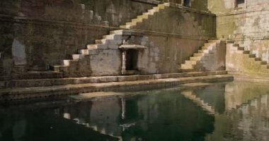 Toorji Ka Jhalra Baoli Stepwell 'deki su deposu. Jodhpur, Rajasthan, Hindistan' daki su kaynaklarından biri. Güneşli bir gün, su tabancaları havuzun duvarlarını yansıtıyor. Kamera yatay tavası
