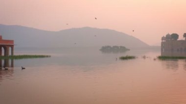 Jaipur 'da gün doğumunda ünlü Hint turist tarihi Jal Mahal (Su Sarayı). Etraftaki ördekler ve kuşlar dingin sabahın tadını çıkarıyorlar. Jaipur, Rajasthan, Hindistan. Yatay tava