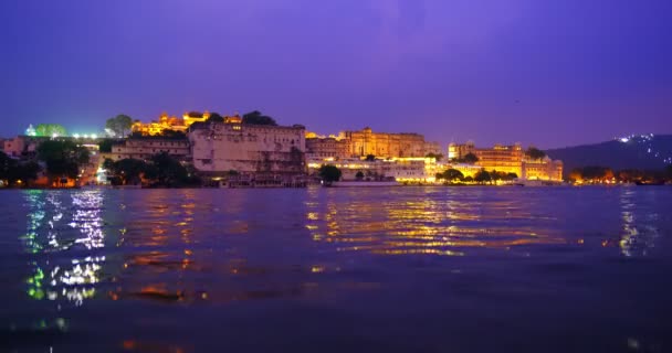 ピコラ湖の岸にある有名な豪華なウディプール シティ パレスは ラージャスターン王朝支配者のラージプット建築である水の波で夕日を照らしました ウディプール インド — ストック動画