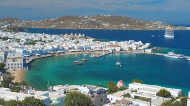 Meşhur yel değirmenleriyle Mykonos kasabası manzarası ve yaz günü tekneleri ve yolcu gemisi olan liman manzarası. Mykonos, Cyclades adaları, Yunanistan. Kamera kaydıyla