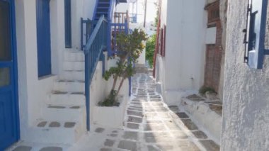 Yunanistan 'ın ünlü Mykonos adasında, Mykonos şehrinin mavi pencereli geleneksel beyaz boyalı evleri ve resimli manzaralı dar caddelerde sabit kameralı bir şekilde yürümek