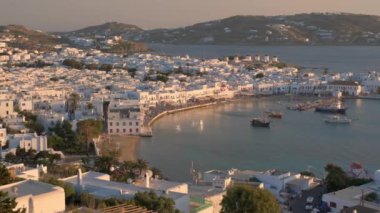 Ünlü yel değirmenleriyle Mykonos kasabası manzarası ve yaz günbatımında tekne ve yatlarla liman manzarası. Mykonos, Cyclades adaları, Yunanistan. Yatay kameralı.