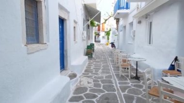 Yunanistan 'ın ünlü Paros Adası' ndaki Naousa kasabasının çiçek açan begonvil çiçekli geleneksel badanalı evleri ile pitoresk dar bir sokakta sabit kamerayla yürümek