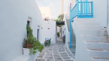 Yunanistan 'ın ünlü Paros Adası' ndaki Naousa kasabasının çiçek açan begonvil çiçekli geleneksel badanalı evleri ile pitoresk dar bir sokakta sabit kamerayla yürümek