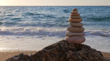 Denge ve uyum kavramı. Taş yığınları gün batımında denizin sahil kıyısında vızıldıyor. Taş istifleme meditasyon sanatı