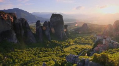 Yunanistan 'ın ünlü Yunan turizm beldesi Meteora' da, Rousanou manastırı ve St. Nicholas Anapavsa Manastırı 'nın üzerinde gün batımı güneş ışınları ve merceklerle parlıyor. Yatay kamera tavası