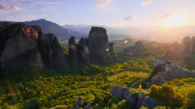 Yunanistan 'ın ünlü Yunan turizm beldesi Meteora' da, Rousanou manastırı ve St. Nicholas Anapavsa Manastırı 'nın üzerinde gün batımı güneş ışınları ve merceklerle parlıyor. Yatay kamera tavası
